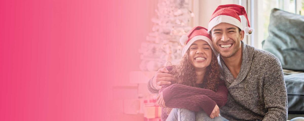 happy latino couple smiling with santa hats on