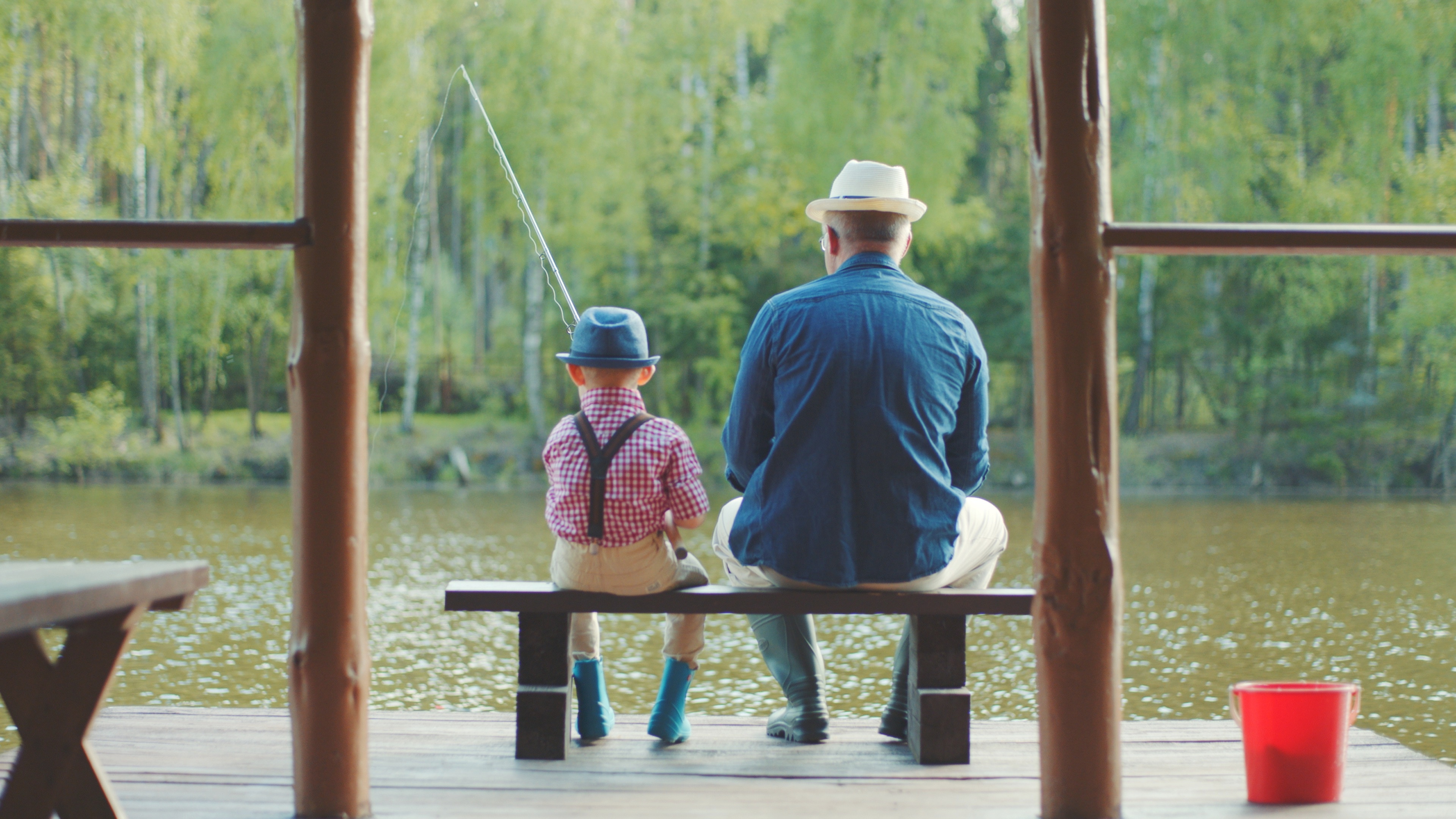 Little boy and his grandpa are fishing at the lake