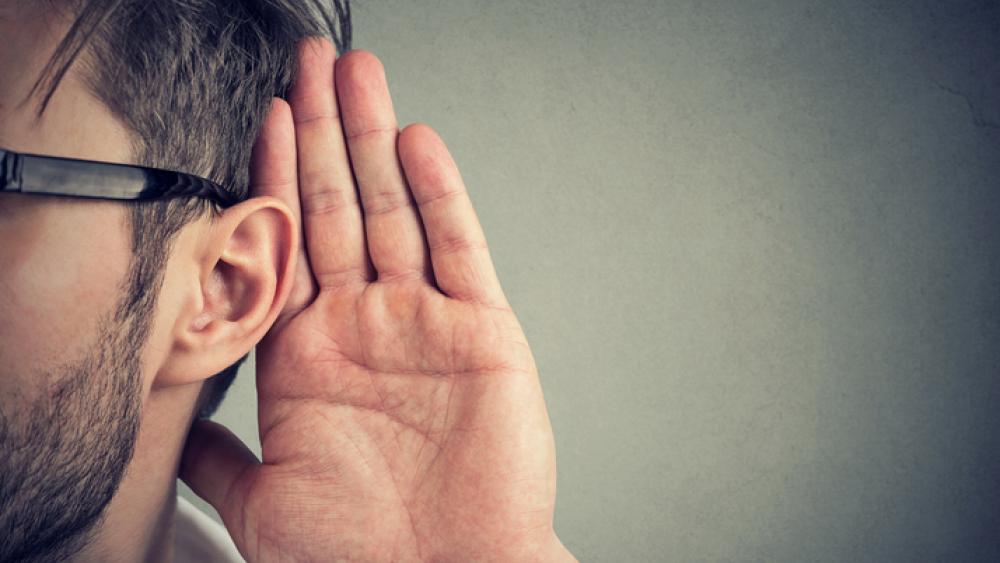 Man holds his hand near ear and listens carefully