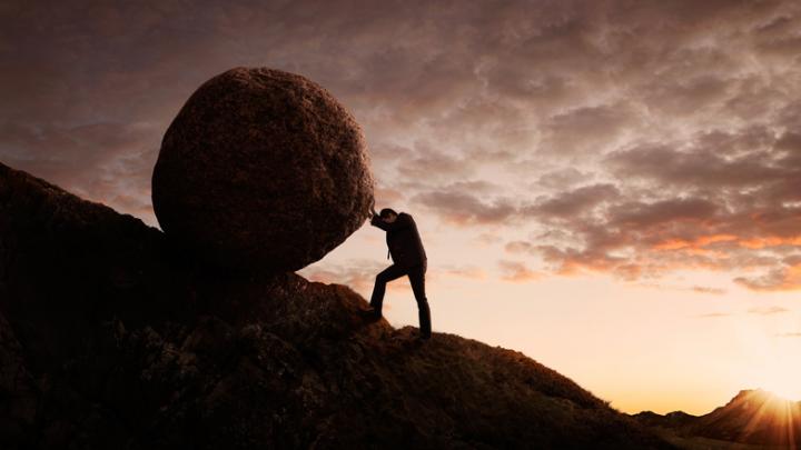 man pushing boulder uphill