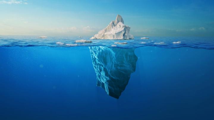 white iceberg floats in the ocean with a view underwater