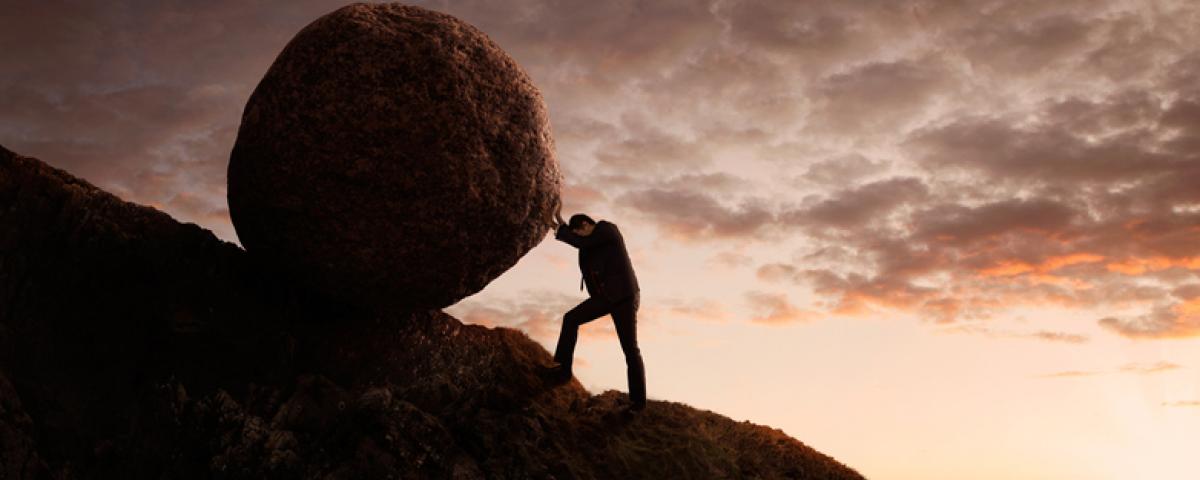 man pushing boulder uphill