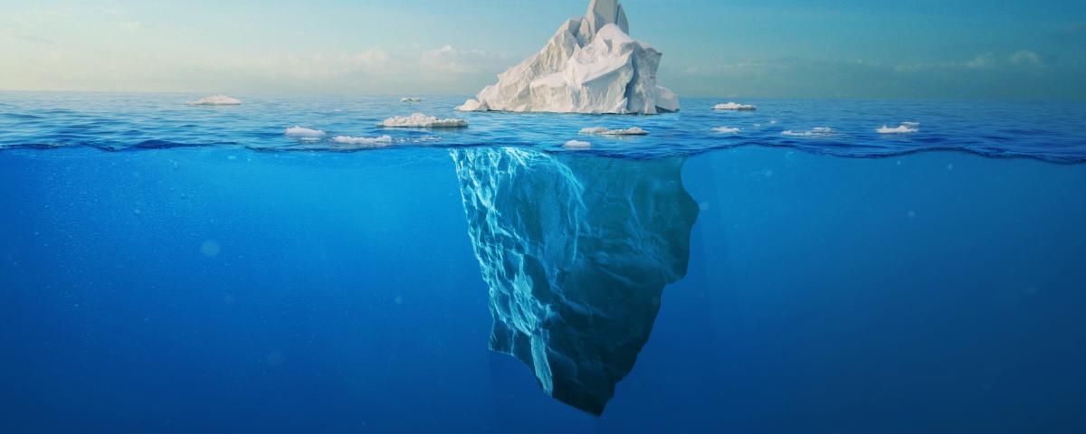 white iceberg floats in the ocean with a view underwater