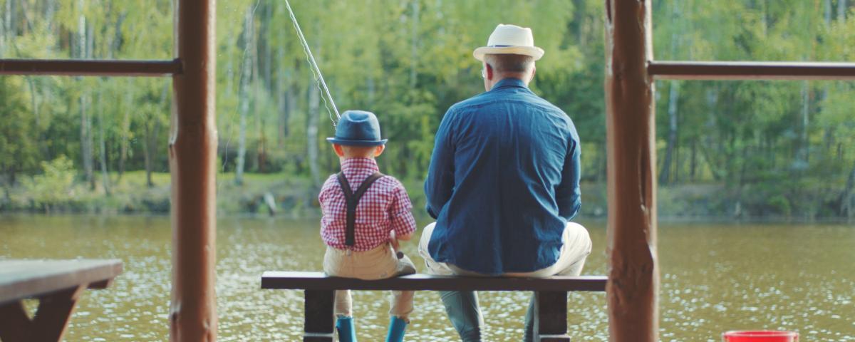 Little boy and his grandpa are fishing at the lake