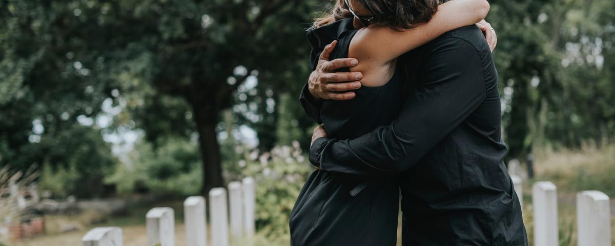Husband trying to comfort his wife at a graveyard